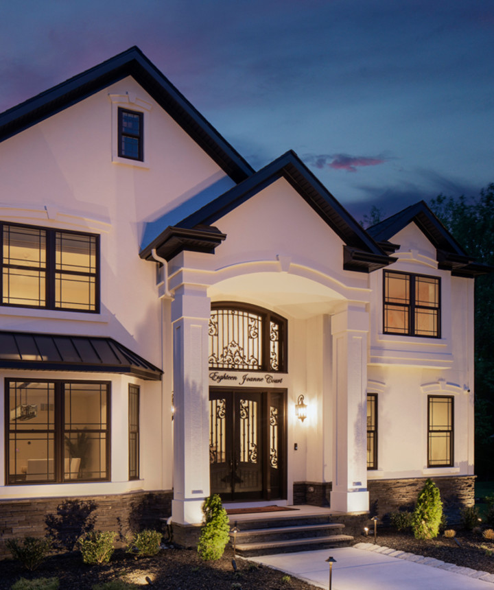 Exterior of home showing detailed door and black windows at evening